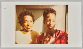 [Two young women standing in sunny room, woman on left wearing silver hoop earrings]
