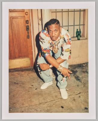 [Man crouching with arms crossed over opposite knees, wearing many bracelets on his left arm]
