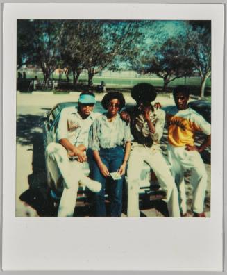 [Group of young adults posing on the hood of a car]
