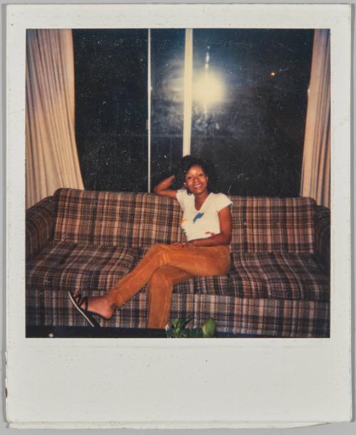 [Women wearing corduroy pants and white t-shirt poses on couch]
