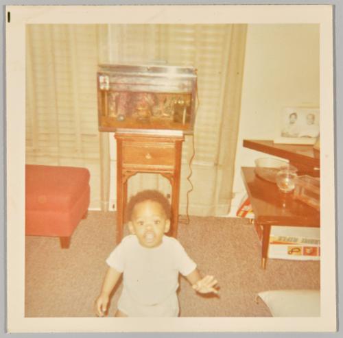 1970 [Toddler standing in living room, fish tank in the background]
