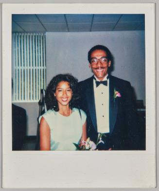 [Man with mustache in a tuxedo poses with woman in light blue dress] 
