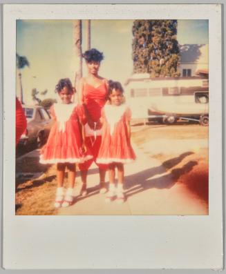 [Young woman posing with twin girls in red]
