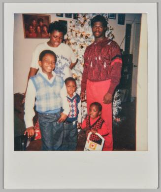 [Family standing in front of Christmas tree, eldest son smiling at camera]
