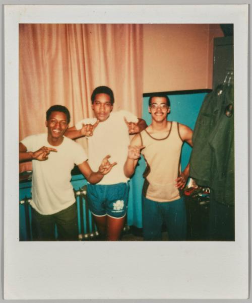 [Three adolescent men posing in atheltic wear making hand gestures]
