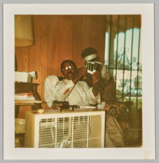 [Man sitting holding five Polaroids in hands]
