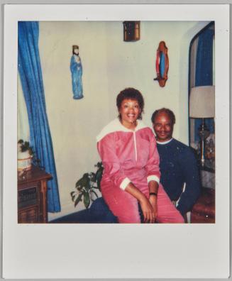 [Woman sitting on man's lap with statue on wall]
