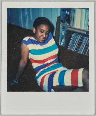 [Woman laying on ground in striped dress beside record shelf]

