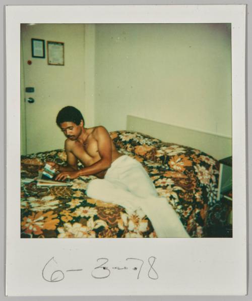 6/2/78 [Young man laying on bed shirtless while reading a newspaper]
