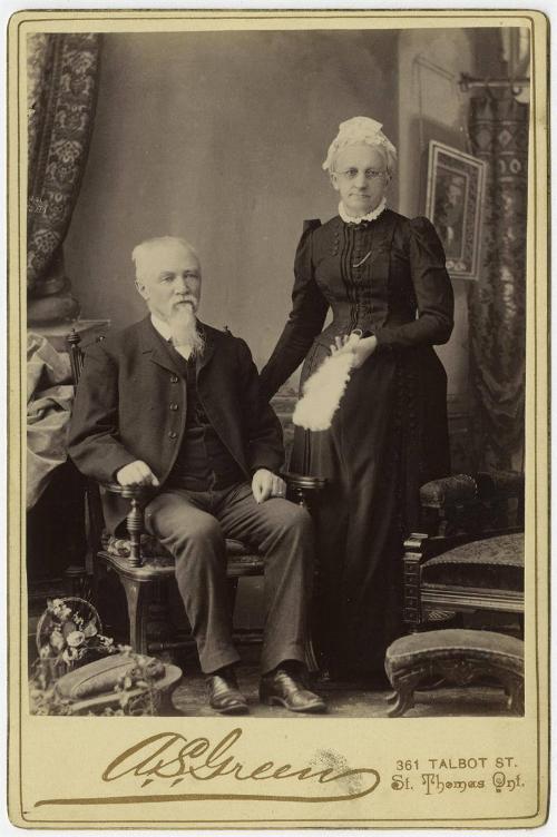 [Older couple, man seated and woman standing]