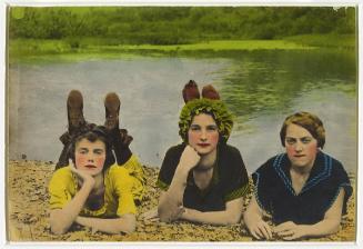 Three women lying on a shore dressed in bathing suits