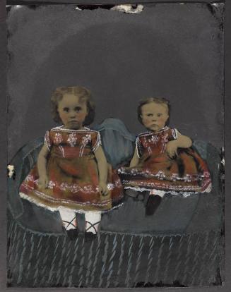 Portrait of two young girls wearing red dresses with white embroidery