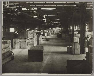 [Warehouse with rows of stacked crates]