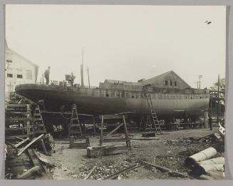 Tug under construction at the Pontbriand Ltée, Sorel, QC [Completed hull of boat with workers and ladders]