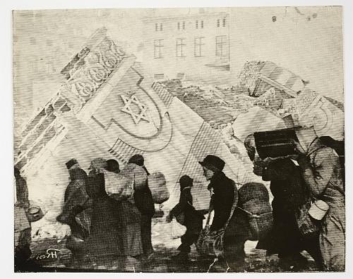 (In photomontage with synagogue in ruins) Boy in cap, with satchel and sack tied to back, walking with winter deportation crowd - side-profile