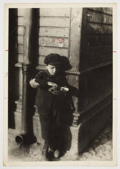 Young boy on a street corner eating from a plate