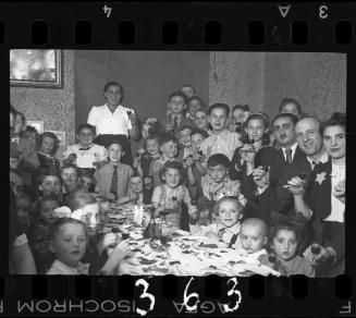 Children and parents gathered around the table at a children's party