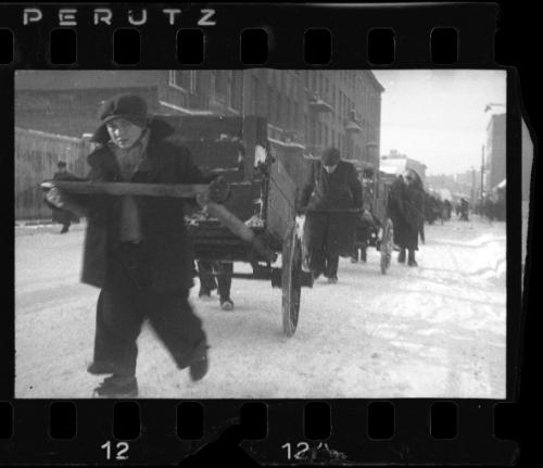 Young boy pulling cart with belongings through the ghetto in winter