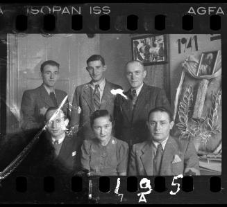 Administrators of the Holzwollefabrik workshop ("ressort") beside a commemorative display, with a portrait of Mordechai Chaim Rumkowski