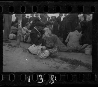 Residents gathered in the street with their belongings, awaiting deportation