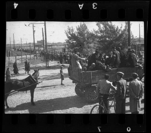 Residents being deported from the ghetto in a horse-drawn wagon, with view of massive deportation in the background