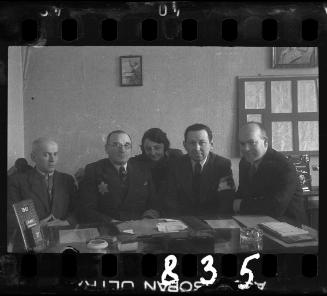 A Jewish policeman and members of the ghetto administration at a desk