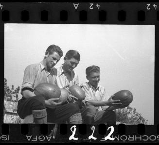 Three men posing with watermelons