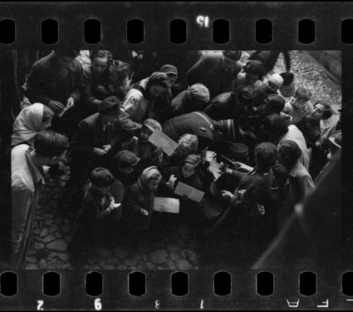 Postal workers distributing mail to a crowd of residents in the ghetto