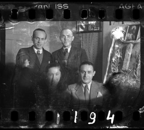Administrators of the Holzwollefabrik workshop ("ressort") beside a commemorative display, with a portrait of Mordechai Chaim Rumkowski