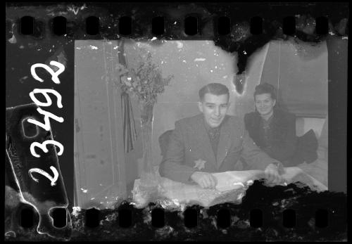 Man and woman sitting at a tabel, with a flower vase and a book