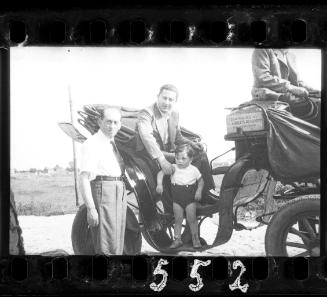 Two men with a boy on a carriage