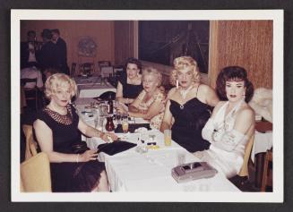 [Anita, Gloria, and friends around a table with cocktails, location unknown]
