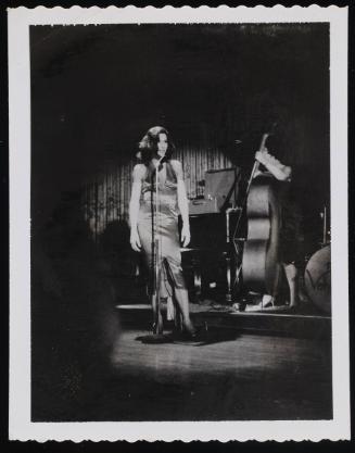 [Singing in a satin dress, location unknown]
